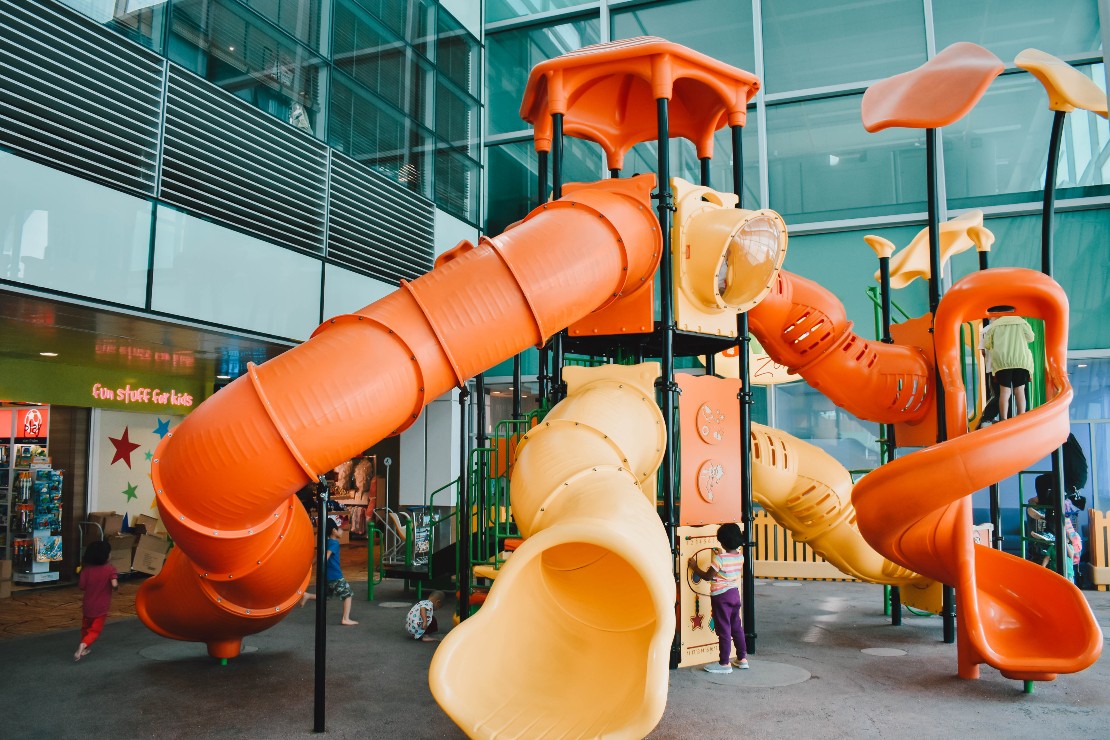 Children play at the playground with tall, big and brightly-coloured slides on all four sides